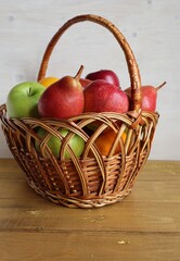 A wicker basket of fruit, apples and pears, stands on the table.