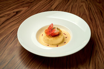 Cheesecake with sauce in a white plate on a wooden background
