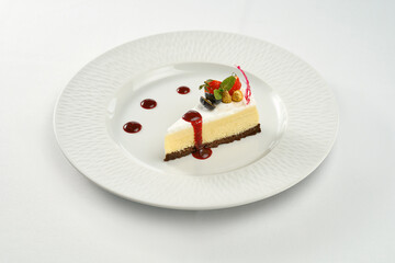 Cheesecake with sauce in a white plate on a white plate