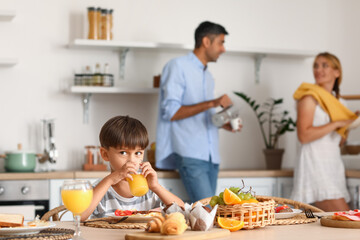 Little boy drinking juice at table in kitchen