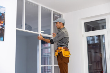 Construction worker installing metal profile for interior partition wall, while building a new...
