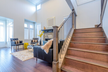 Beautiful and large living room interior with hardwood floors and vaulted ceiling in new luxury home. View of entryway, and second story loft style area