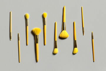 Different makeup brushes on grey background