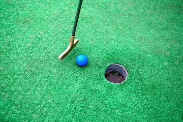 golf club rolls a point into a hole in a golf course, close-up