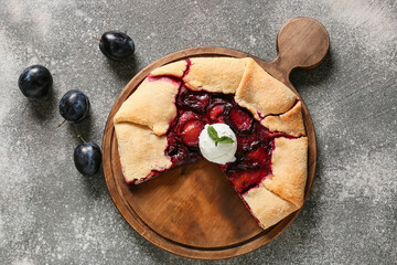 Board with tasty homemade plum galette on grunge background