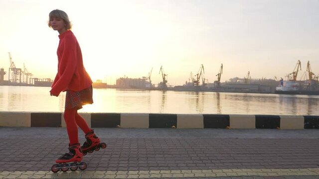 Cute teenage girl rollerskating at sunrise, urban sports, fun leisure activity in sea port, teenage lifestyle