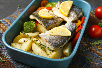 Baking dish of delicious sea bass fish with vegetables on table