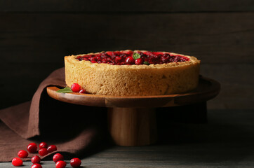 Stand with delicious lingonberry pie on dark wooden table