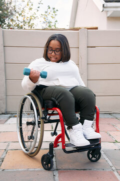 Woman in a wheelchair lifting weight at home