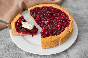 Plate with tasty lingonberry pie and dip on grey background