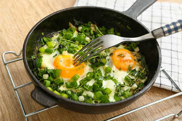 Frying pan with tasty Shakshouka on wooden background