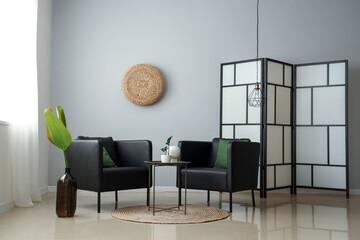 Interior of stylish living room with modern armchairs and folding screen