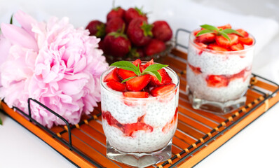 A healthy breakfast dessert with strawberries, yogurt and chia seeds on a wicker tray. Delicious natural and healthy dessert. Сlose-up.