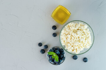 Homemade cottage cheese with blueberry and honey on gray background. Healthy breakfast concept. Selective focus. Top view. Copy space.