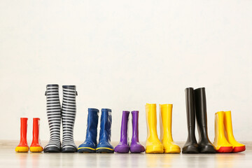 Many different rubber boots on floor near light wall