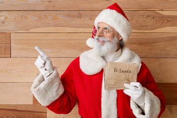Santa Claus with letters showing something on wooden background