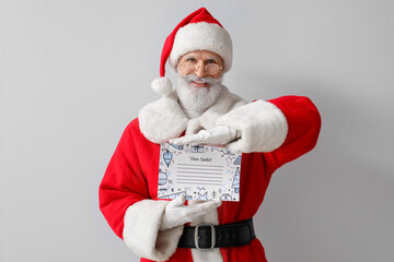 Santa Claus with empty letter on grey background