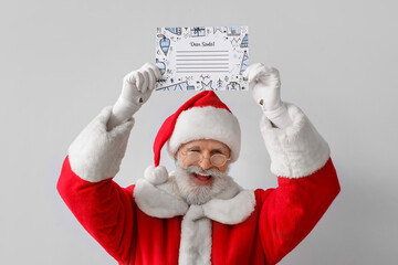 Happy Santa Claus with empty letter on grey background