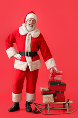 Happy Santa Claus with letters and gifts on sledge against color background