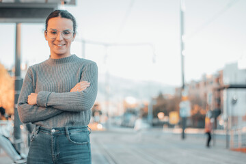 Mujer joven caminando por la estación de tren con felicidad de brazos cruzados