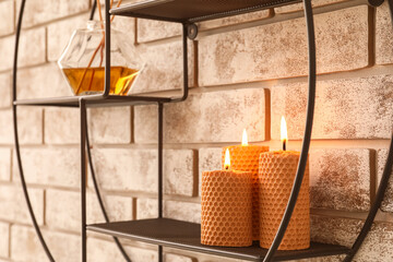 Shelf unit with beautiful burning candles on brick wall
