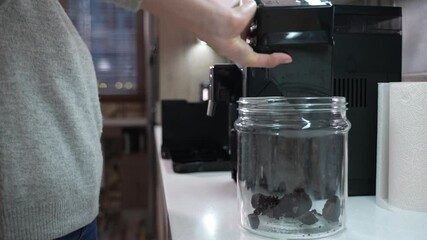 Girl is servicing the domestic coffee machine and collecting coffee grounds for recycling. High quality 4k footage 