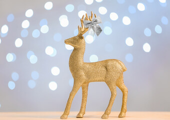 Golden reindeer and bow on table against light background