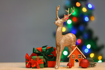 Golden reindeer and Christmas decor on light table against blurred background