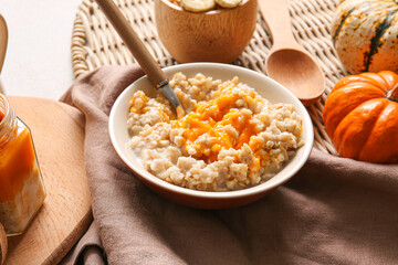 Bowl of tasty oatmeal with pumpkin on table