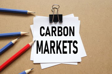 CARBON MARKETS. text on white sticker on wood background