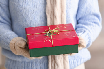 Woman with beautiful Christmas gift on blurred background