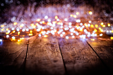 christmas garland of white and golden defocused lights on dark old weathered vintage table or wooden brown board. Christmas decoration, New Years Eve. Selective focus, bokeh, space for text.