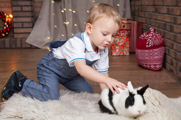 Cute kid playing at home with a live rabbit for Christmas