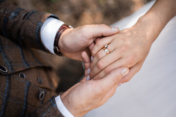 groom holds hand with bride's ring, bouquet