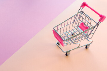Shopping cart on pink and light yellow background