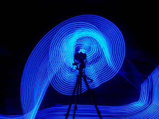 A camera on a tripod in the center of darkness art photography