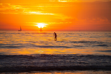 Paddle boarding. Calm sea with sunset sky and sun through the clouds over. Ocean and sky background, seascape.