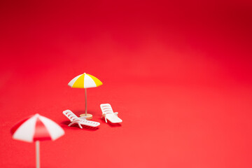 Obraz premium Two sun loungers and red umbrellas on a red background.