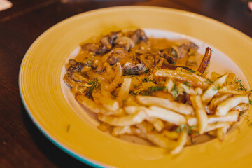 Potato wedges with dill and sauce in an orange plate. Stripes. Food. Eating. Prepared. Serving. Nutrition
