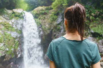 Back view of woman traveler enjoying a waterfall, enjoys nature while traveling