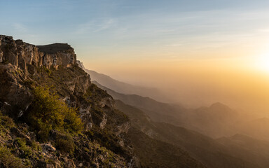 Sunrise Over Jabal Samhan's Peaks. The first light of day breaks over the rugged peaks of Jabal Samhan in Oman, casting a warm glow on the natural landscape.