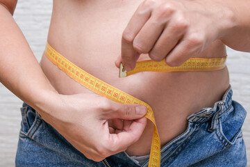 Fat overweighted woman measuring her stomach, belly, diet and losing weight concept