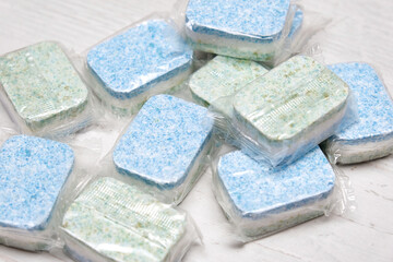 Many green and blue dishwasher tablets in water-soluble packaging close up