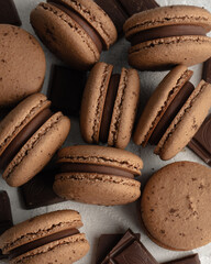 Chocholate macarons arranged randomly on white background with pieces of chocolate between