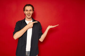 young, handsome, excited man in casual clothes, blue shirt, white T-shirt, points index finger...