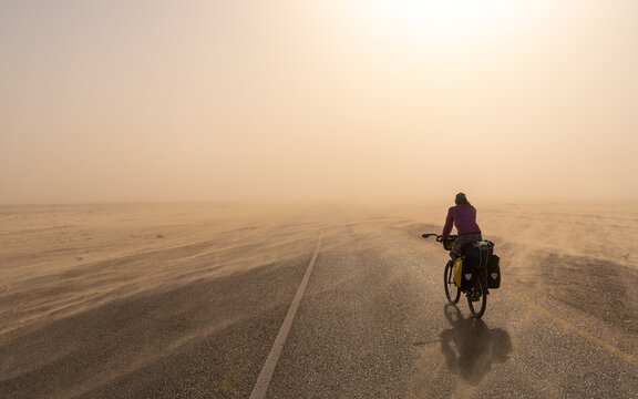 Person Riding A Bike In The Desert During A Sand Storm 