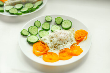 Soft focus,  breakfast plate. Selective focus. Sliced cucumber, fried scrambled eggs close up.