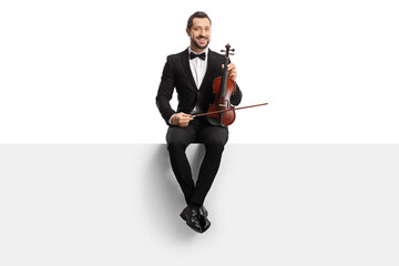 Male violinist with a bow tie sitting on a panel and holding a violin