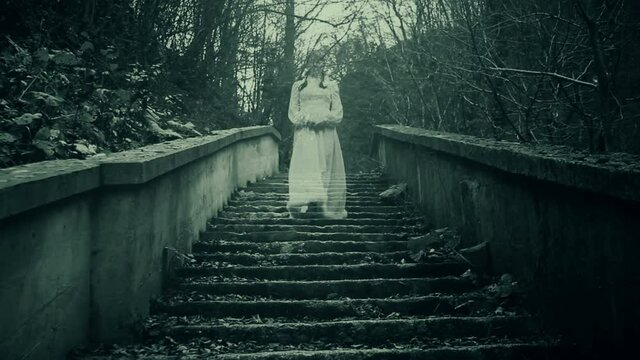 Haunted woman in white dress walking down the stairs