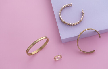 Flat lay of golden modern bracelets on pastel colors background with copy space